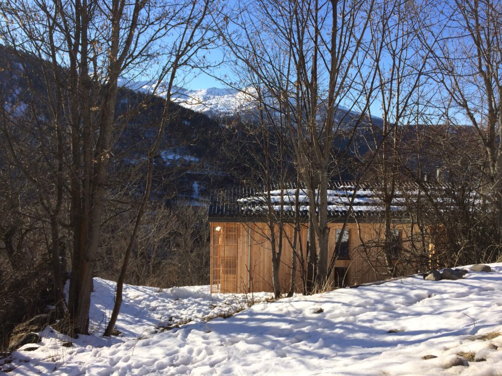 Gîte des Mille Thabor à Valmeinier : implantation du bâtiment dans un terrain de haute de montagne, entre végétation et relief.