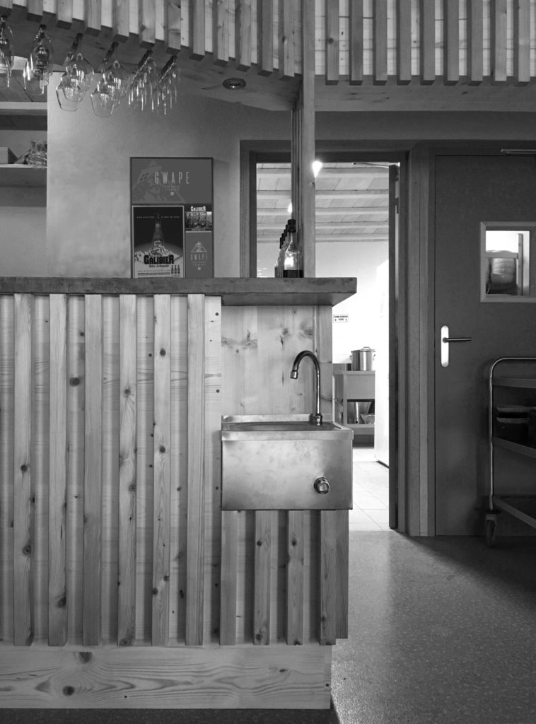 Bar du Refuge de Terre Rouge à Valmeinier : des petites fonctionnalités sont ajoutées au meuble comme une fontaine à eau dans un des angles du meuble.